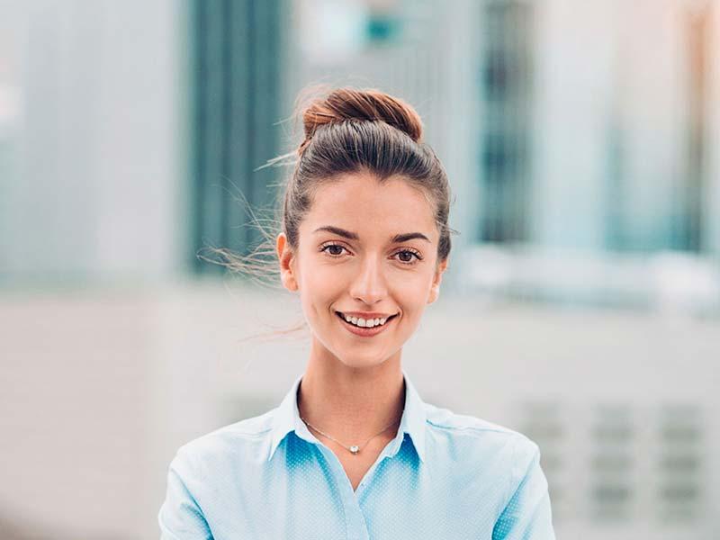 Smiling young woman in a blue shirt with a blurred city background