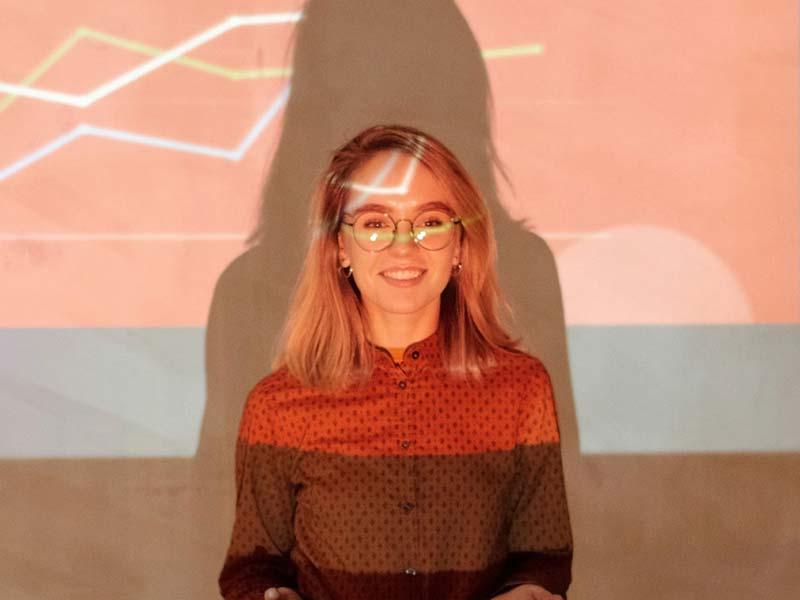 Smiling woman giving a presentation with projected data on the screen